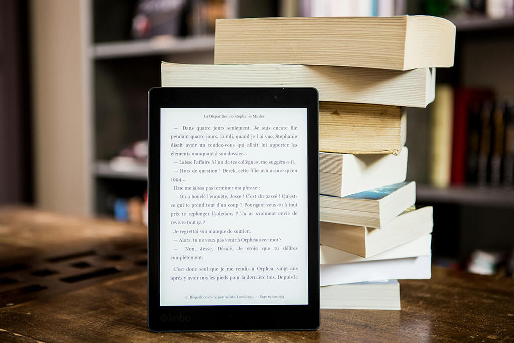 Photo of a black tablet computer supported by a vertical pile of books.